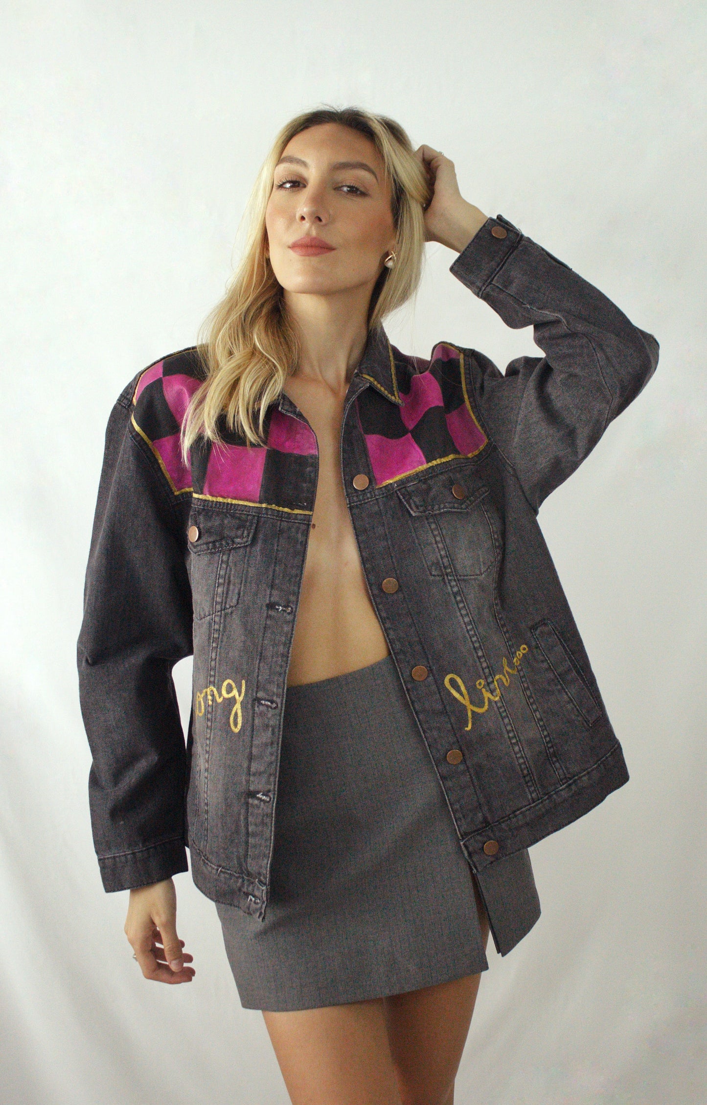 Distressed black women’s jean jacket with a handcrafted chessboard and colorful accents in orange, blue, and violet.