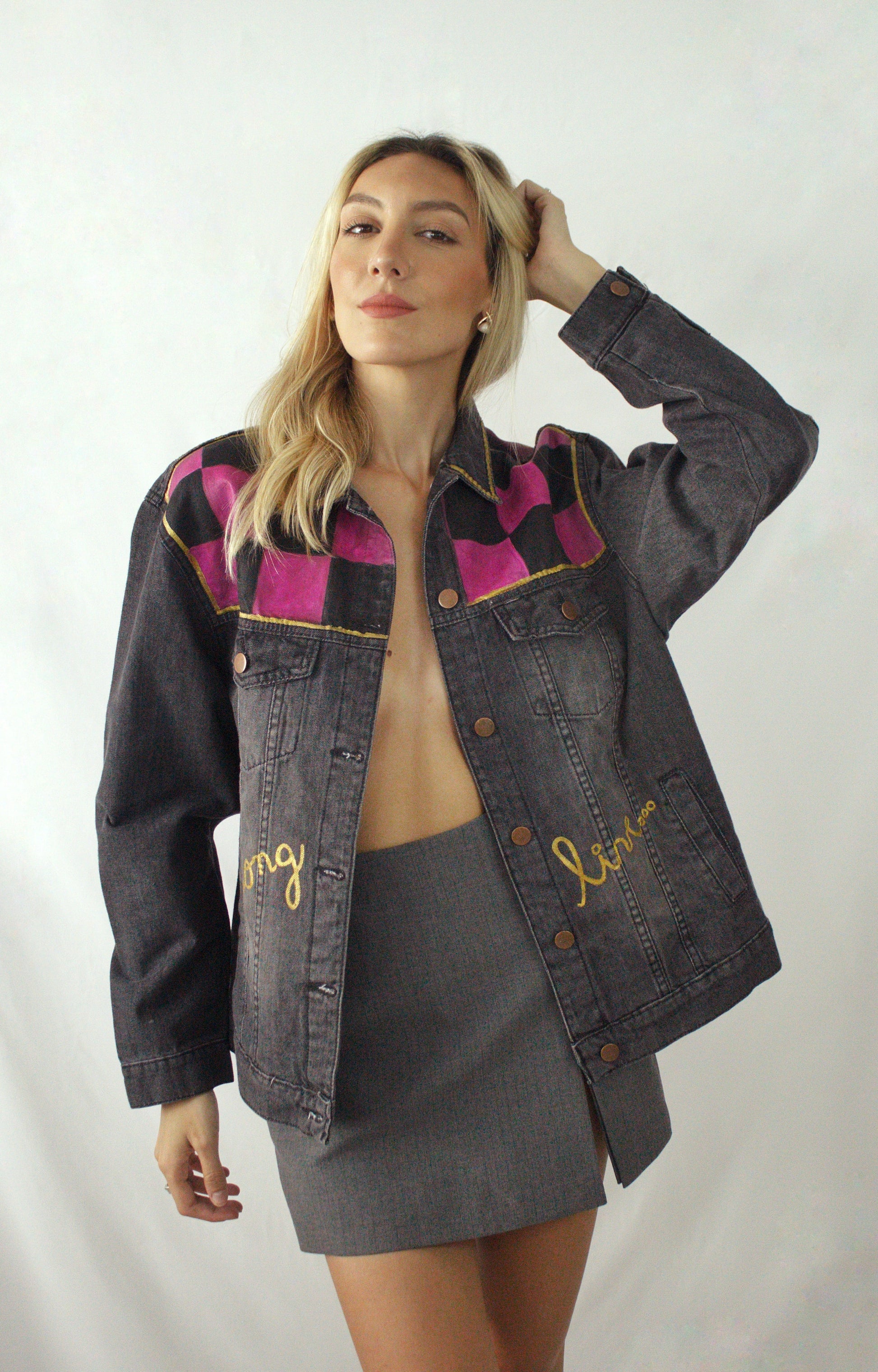 Distressed black women’s jean jacket with a handcrafted chessboard and colorful accents in orange, blue, and violet.