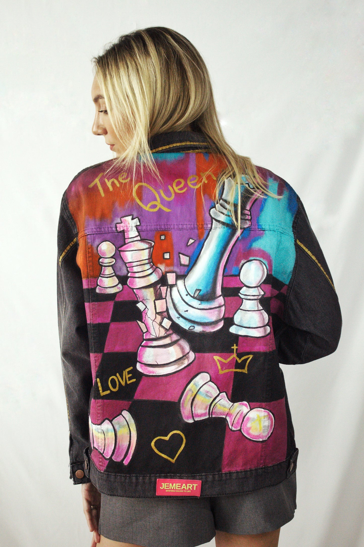 Hand-painted denim jacket for women featuring a black and fuchsia chessboard design with the phrase "Long Live the Queen."