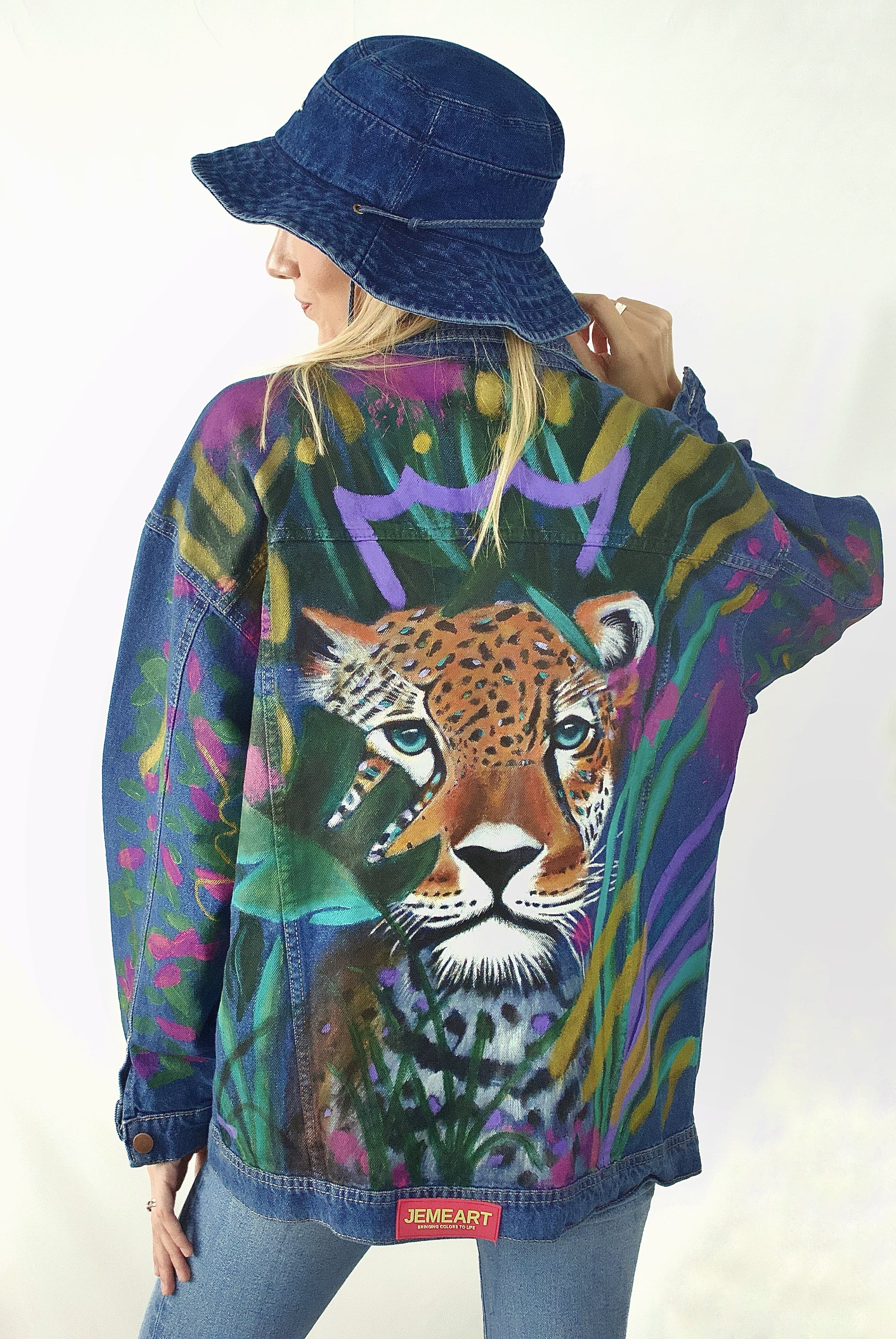 Hand-painted oversized denim jacket for women featuring a crowned leopard and tropical leaves in vibrant colors.